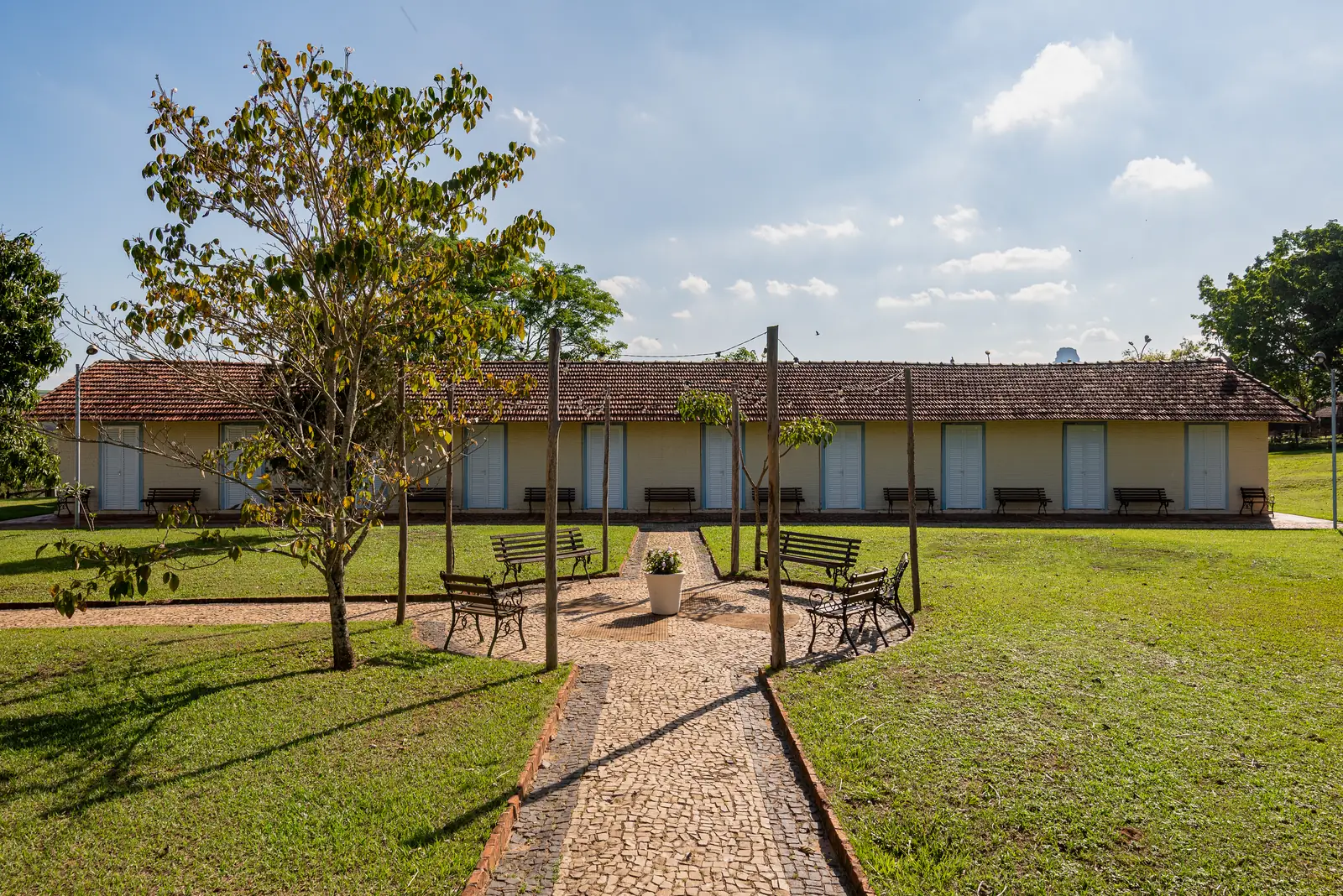 Bloco de apartamentos diante do jardim, com caminho de pedra e bancos