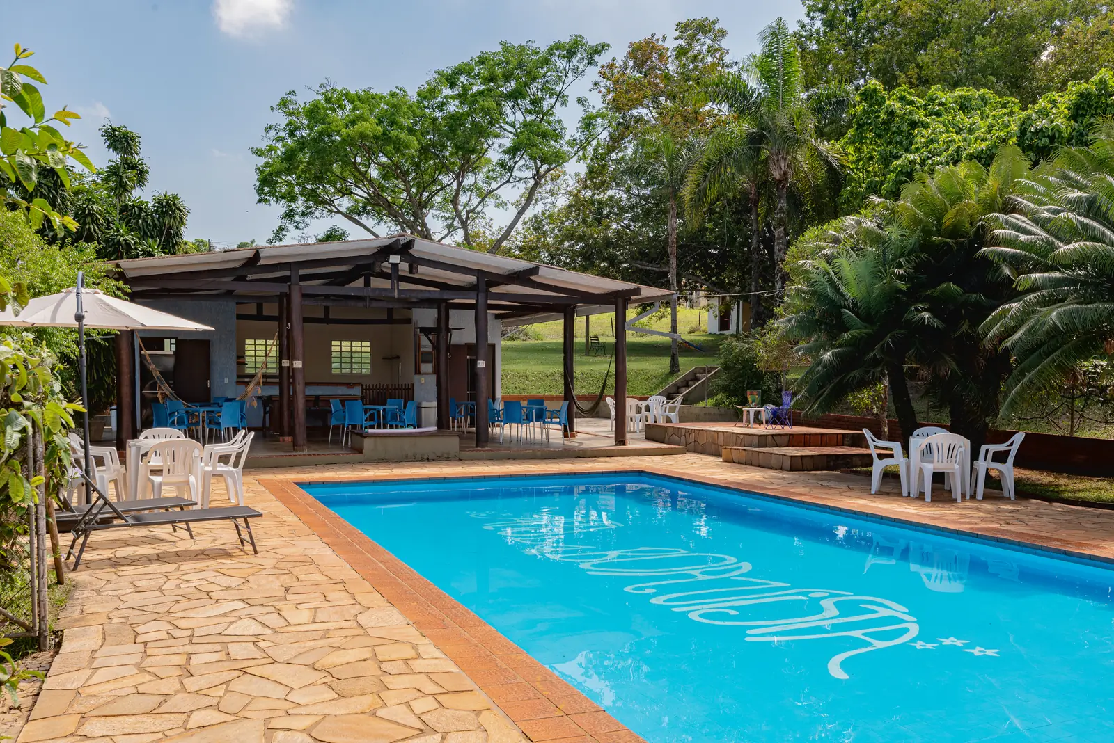 Piscina com o quiosque e as mesas ao fundo