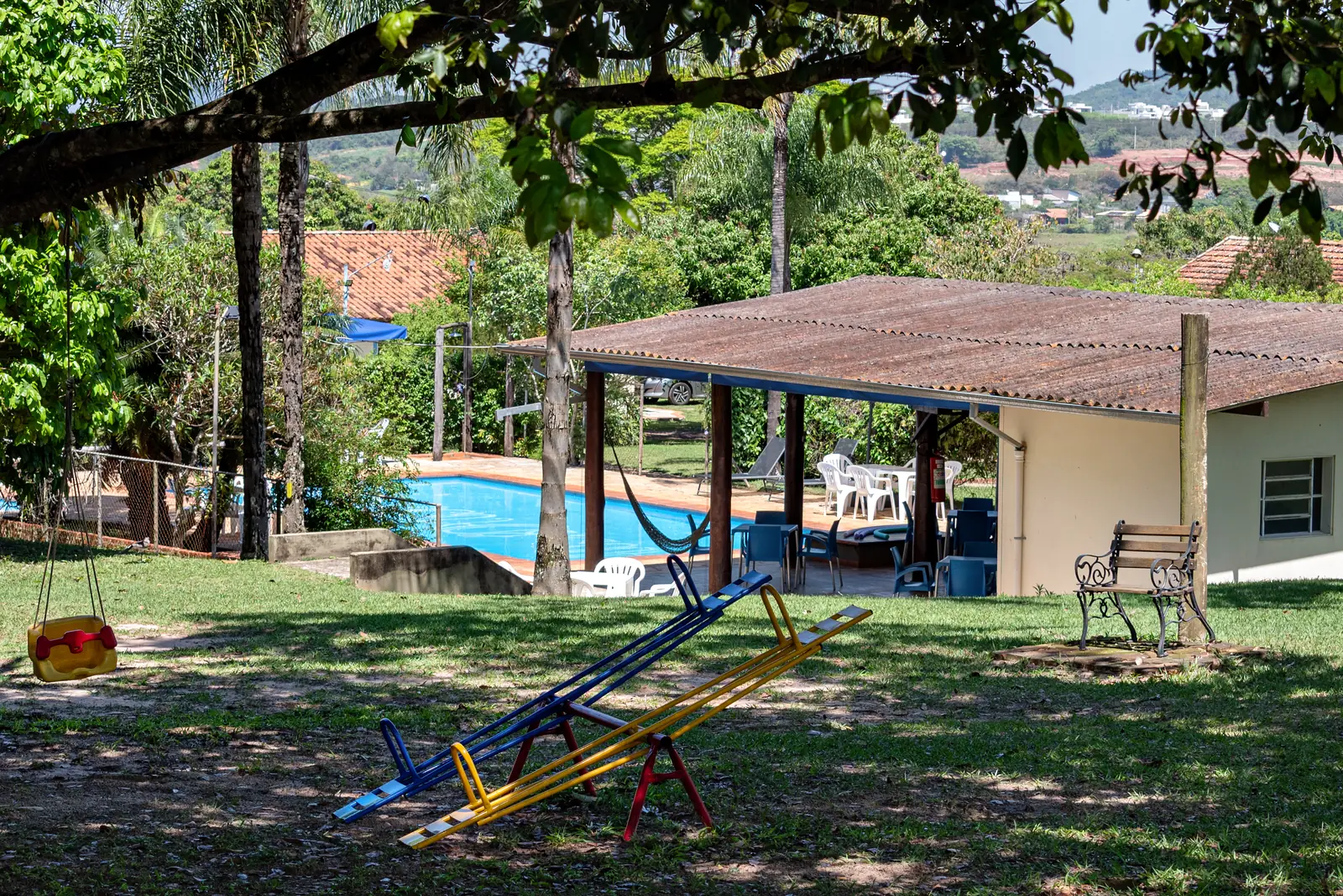 Playground com gangorra e a piscina ao fundo